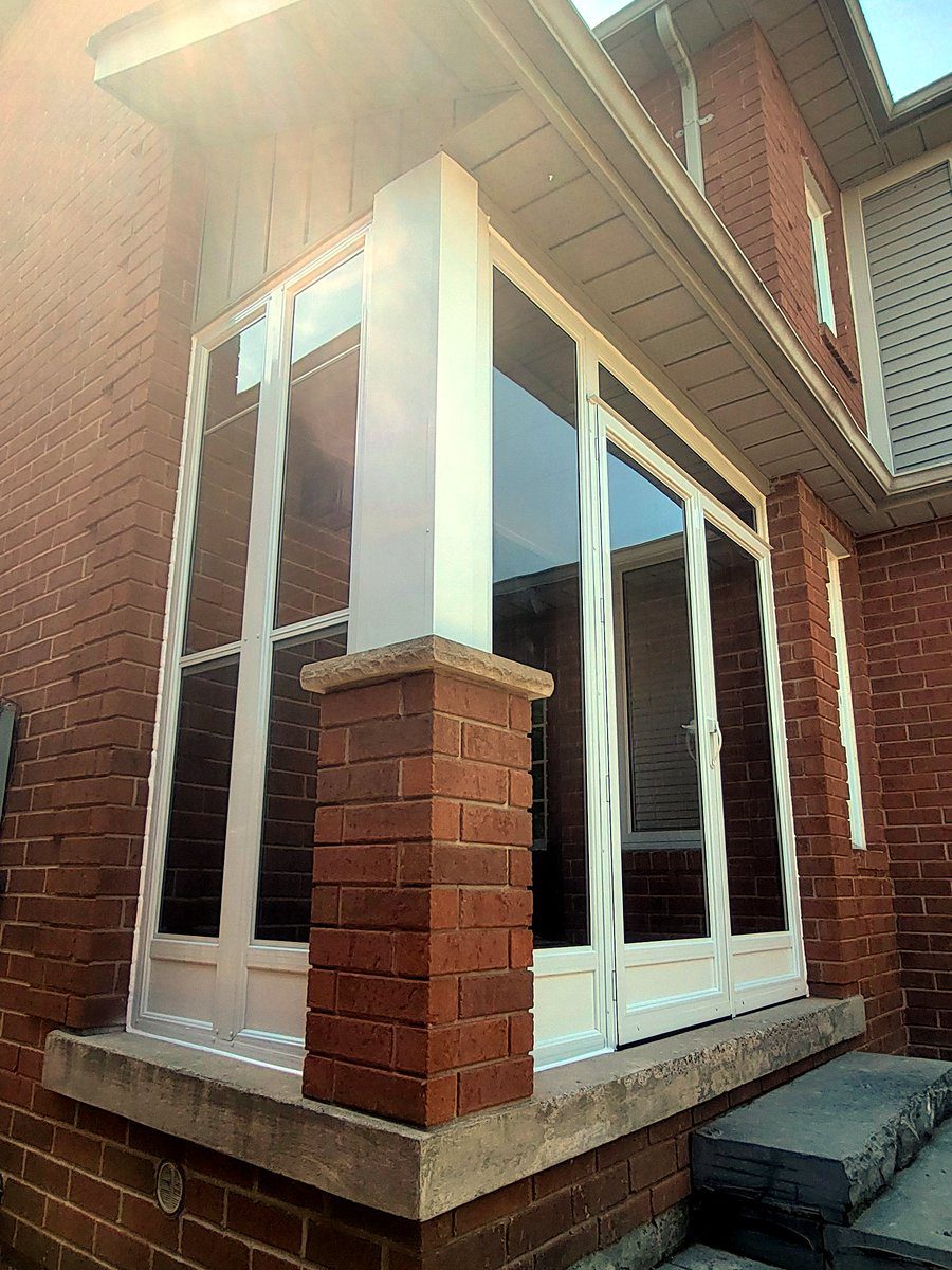 Custom winterized front porch enclosure integrated seamlessly into exterior brick entryway