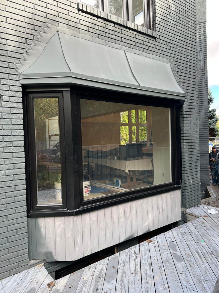 Custom black panoramic picture bay window retrofit with flanking low-E casements