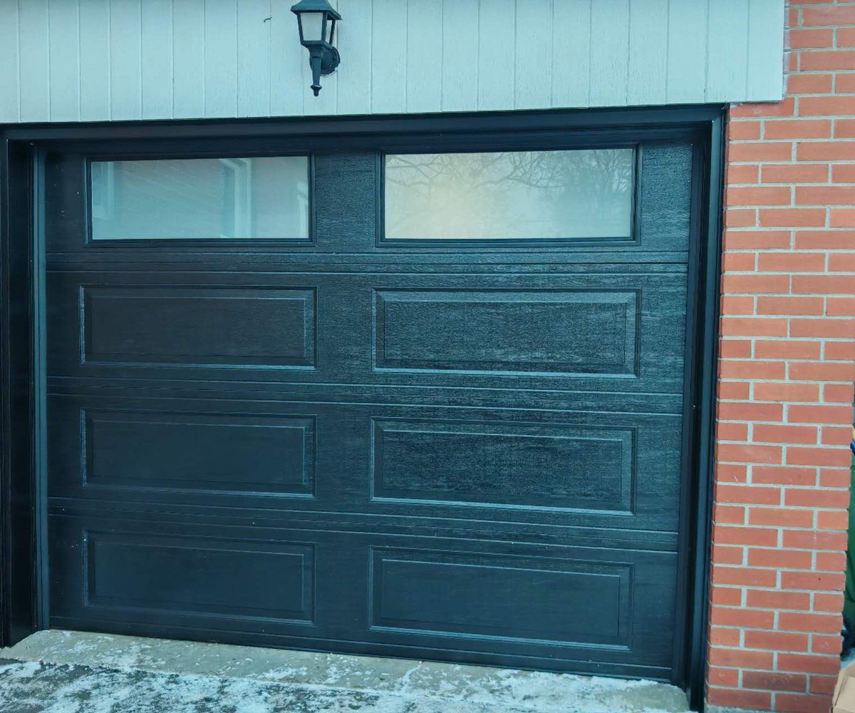 New black woodgrain garage door with window inserts after replacement