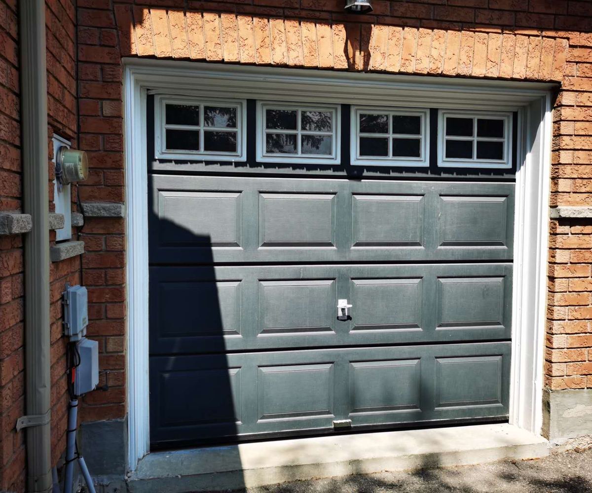 Faded grey garage door before replacement on a Vaughan brick home